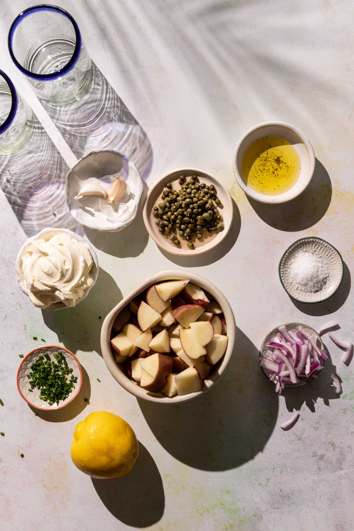 Potatoes, lemon, capers, red onions, and garlic in bowls