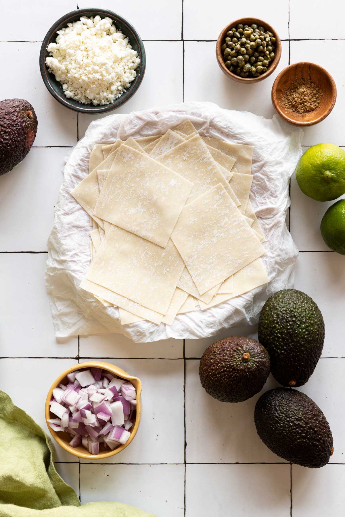 Wonton skins on a plate with avocados, limes, and goat cheese