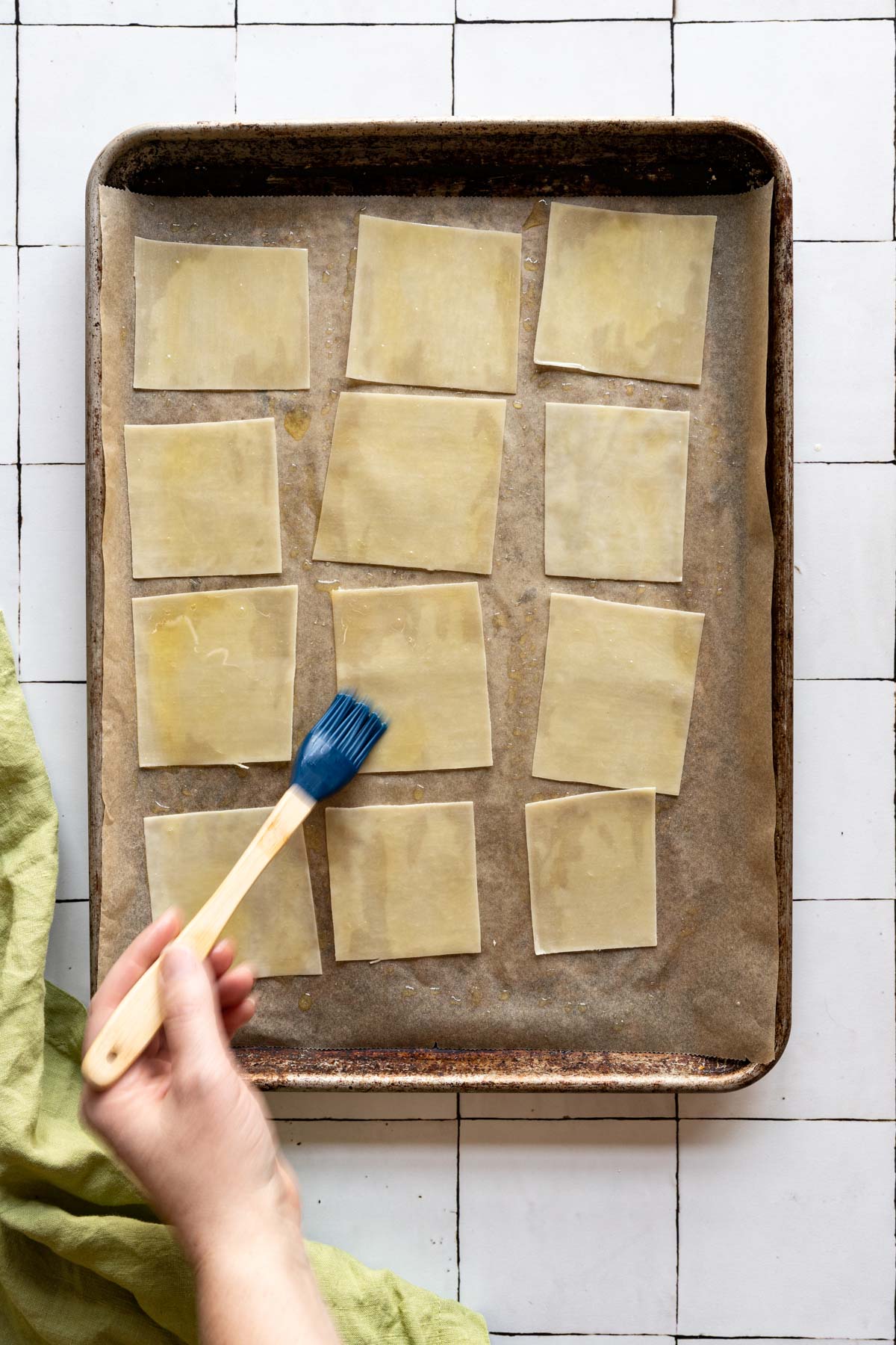 Wonton skins being oiled with a pastry brush