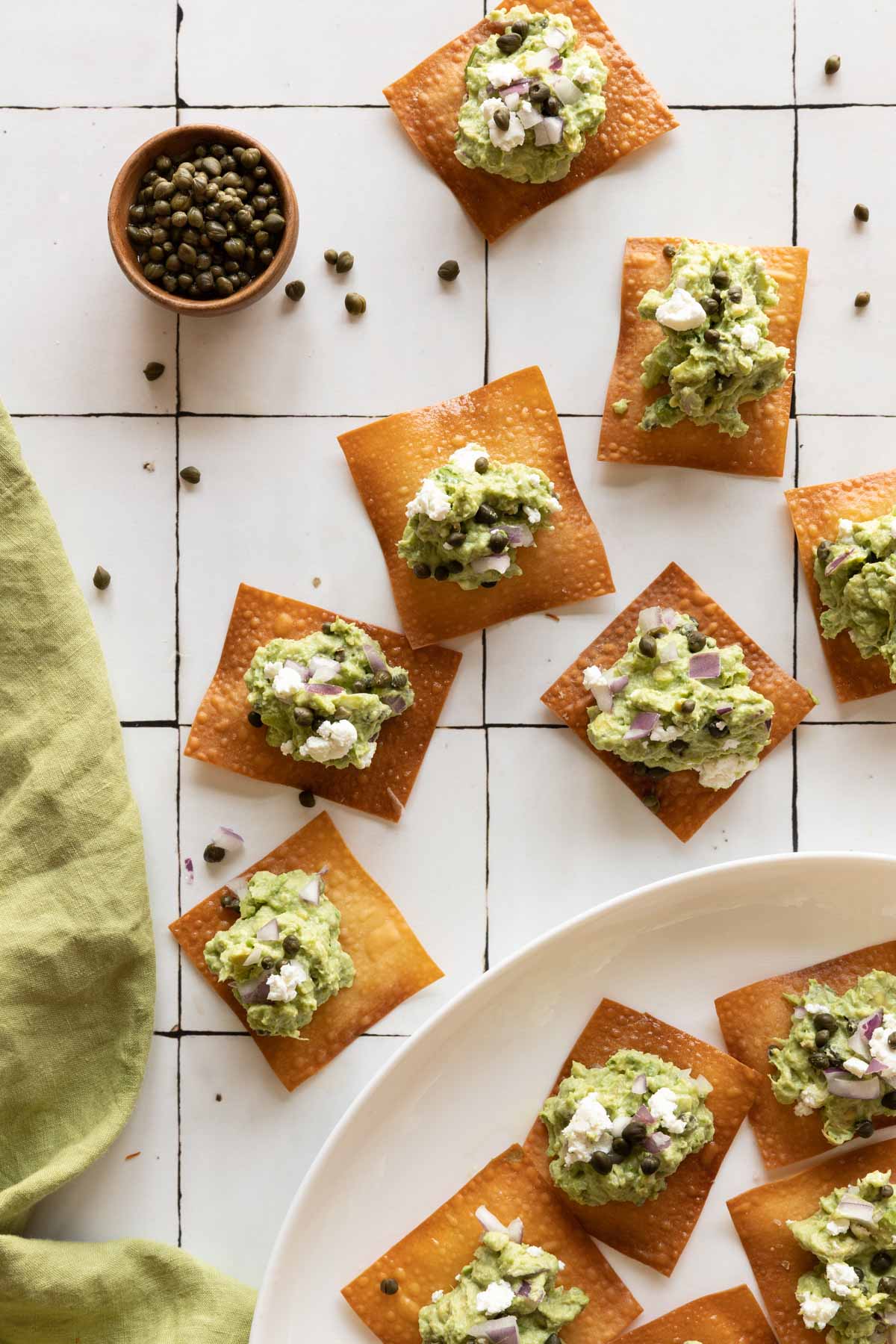 Wonton skins topped with guacamole on a plate