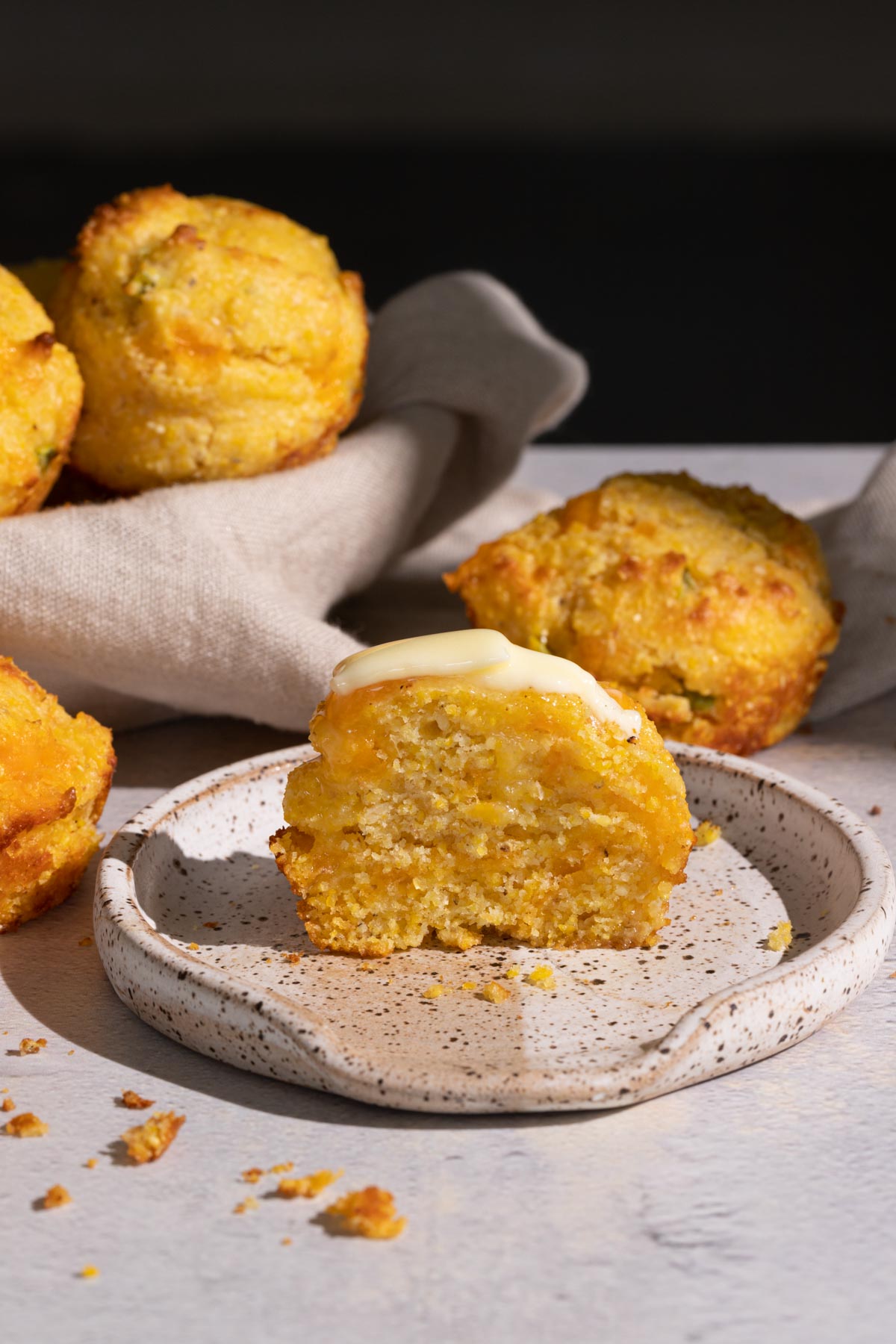 Jalapeno cheddar cornbread muffin on a plate cut in half