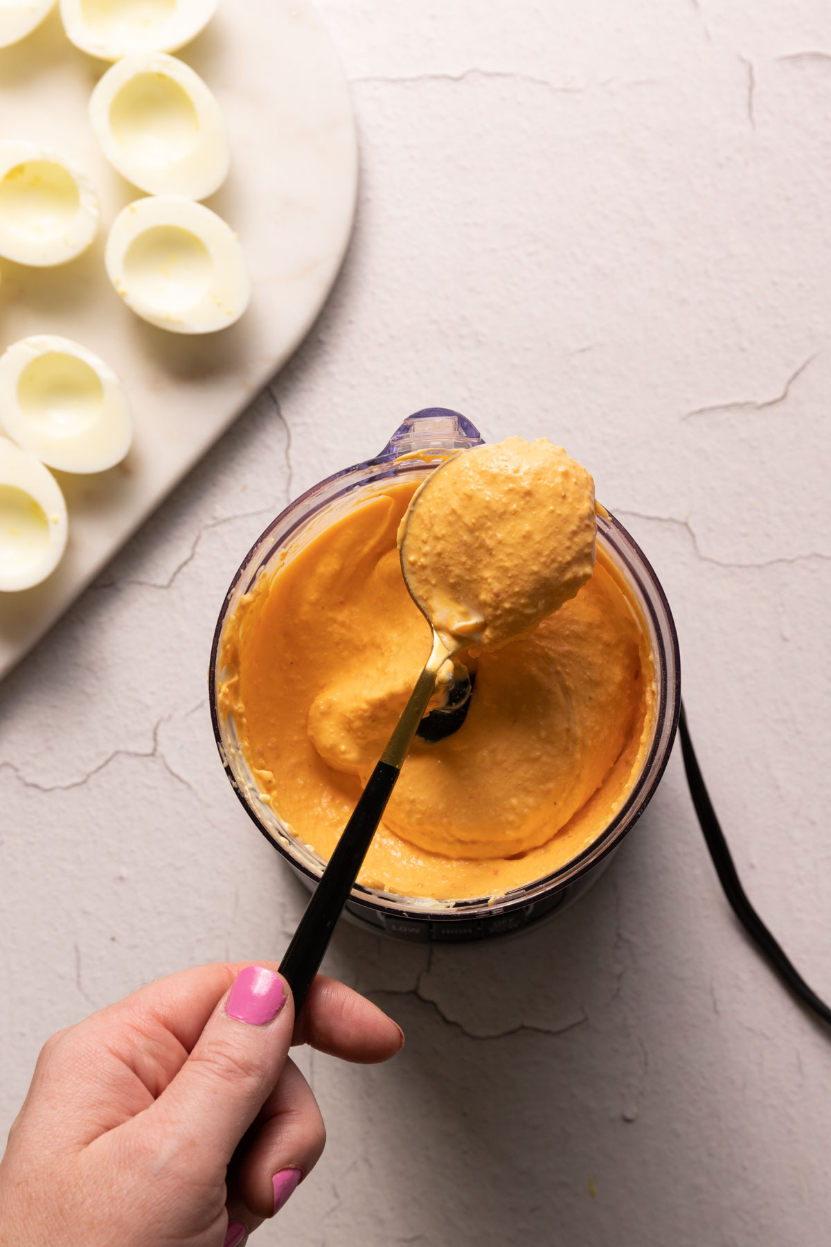 Pimento deviled egg filling in a food processor with a spoon