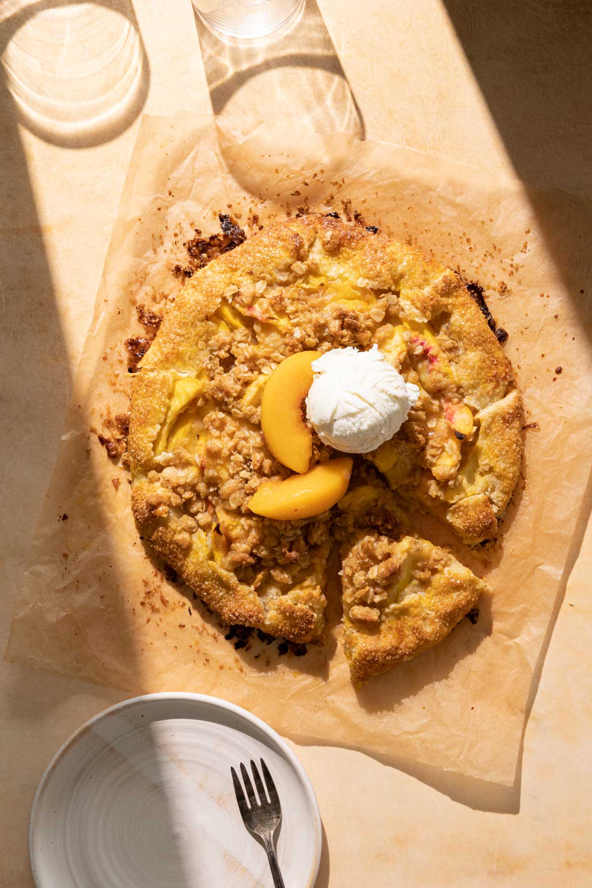 Peach Crostata on parchment paper with a scoop of ice cream