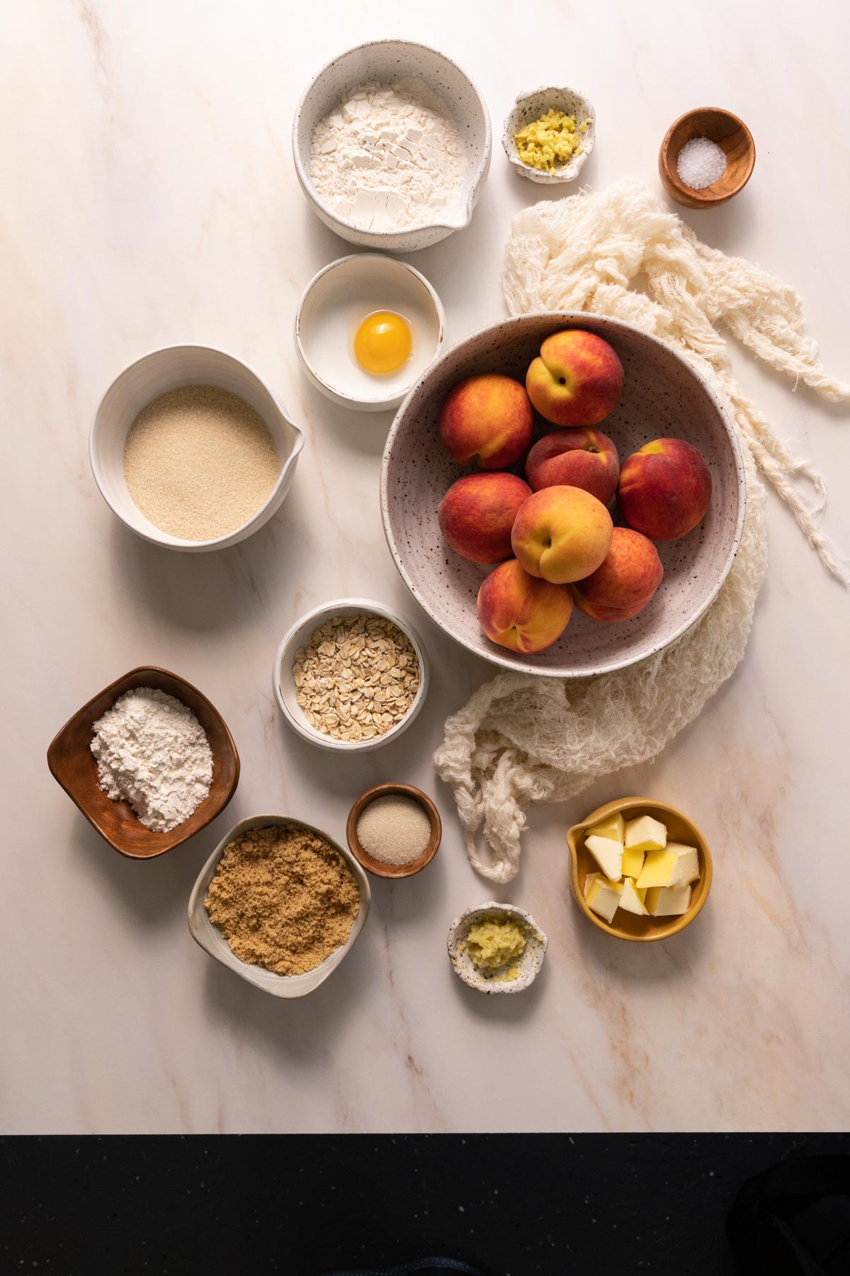 Bowls of peaches, flour, sugar, butter, and oats for a peach crostata