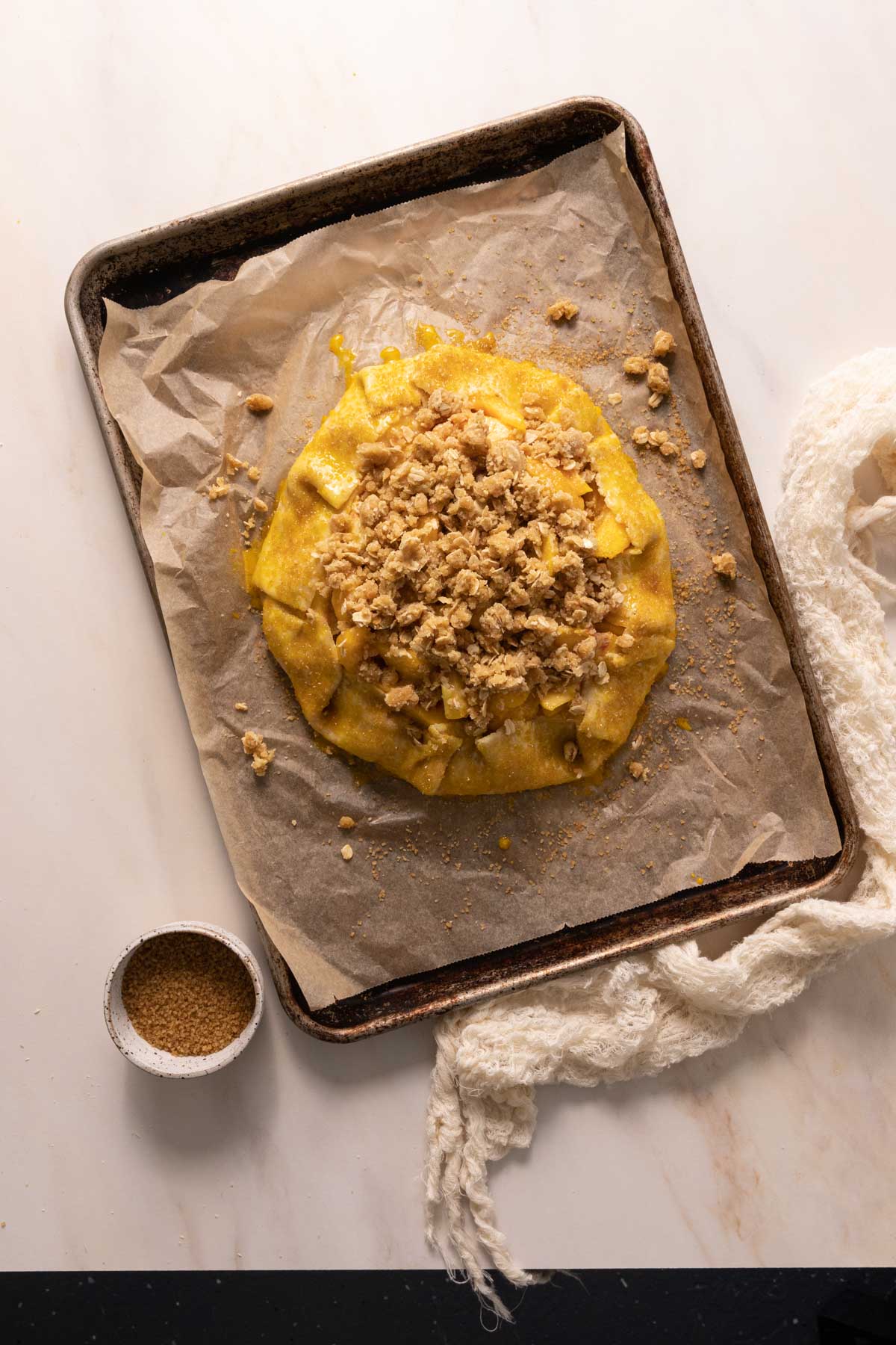 a peach crostata with sugar sprinkled on a sheet pan