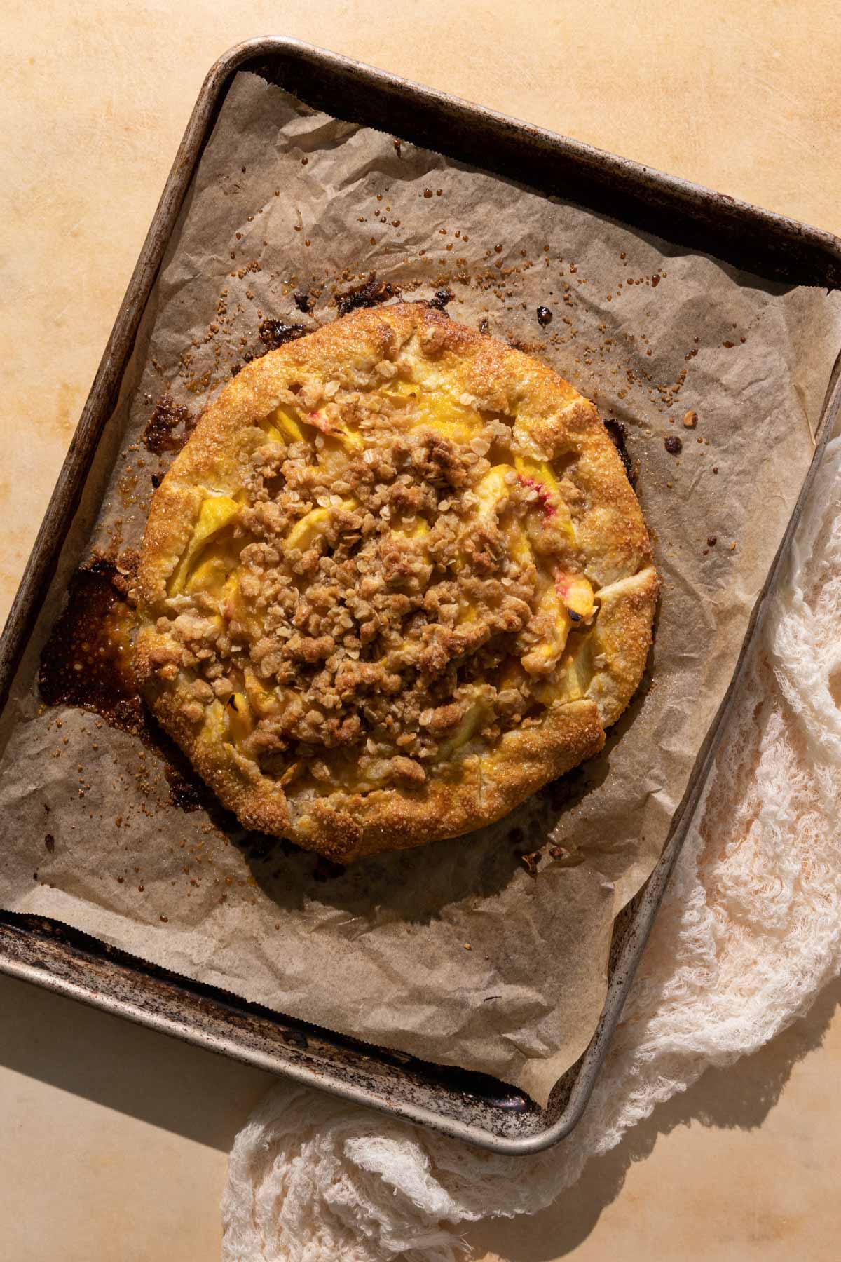 A baked peach crostata on a sheet pan