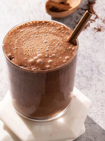 Iced chocolate coffee smoothie in a glass with a metal straw