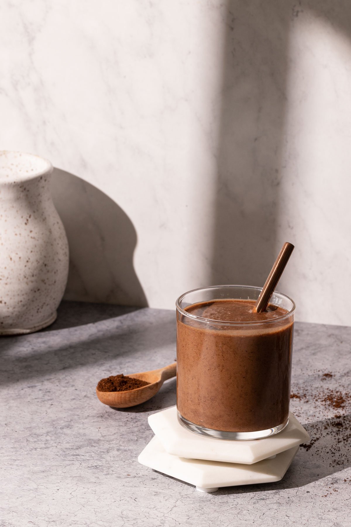 A glass of Iced chocolate coffee smoothie in the sun with shadows on the wall