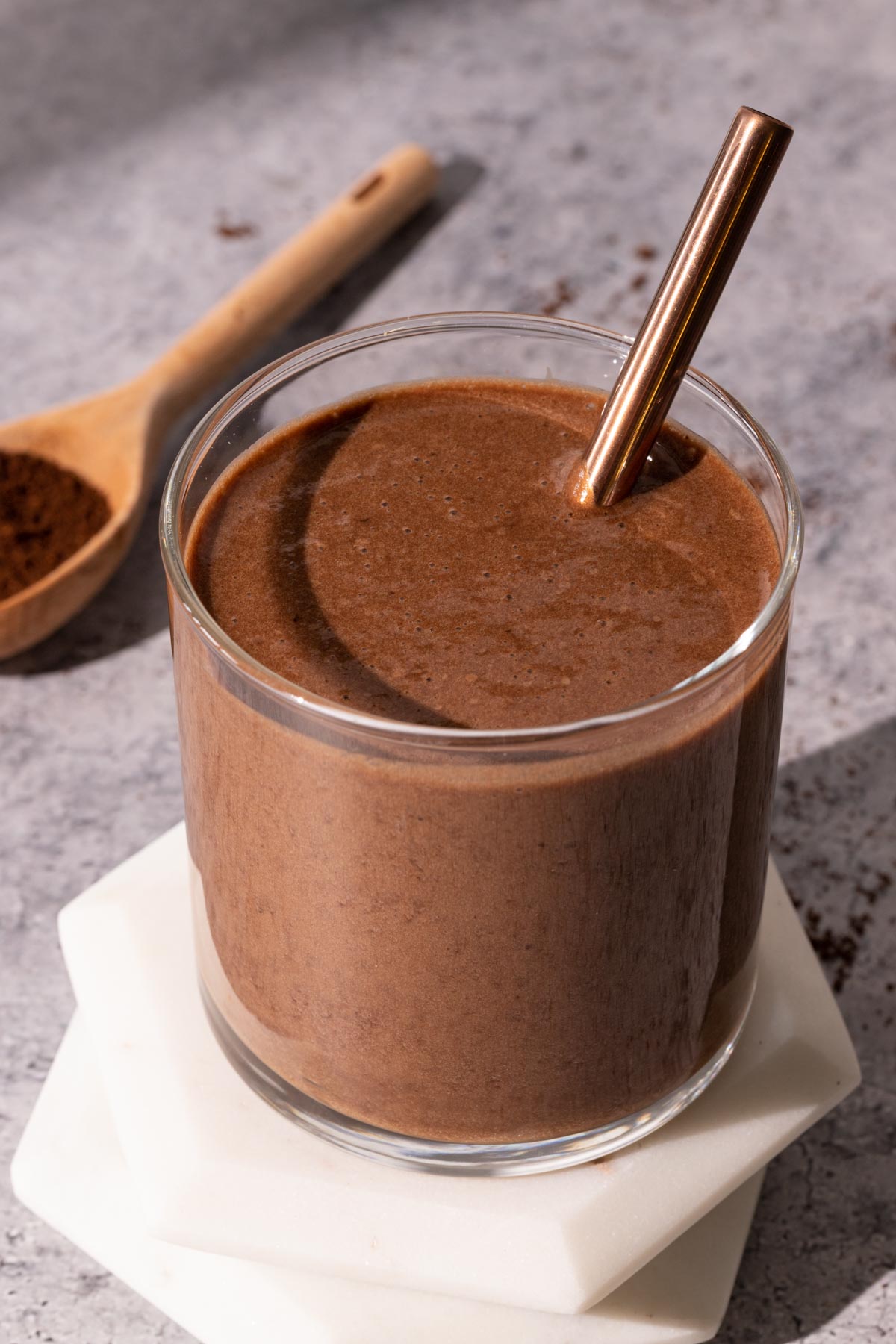 Iced chocolate coffee smoothie in a glass with a metal straw