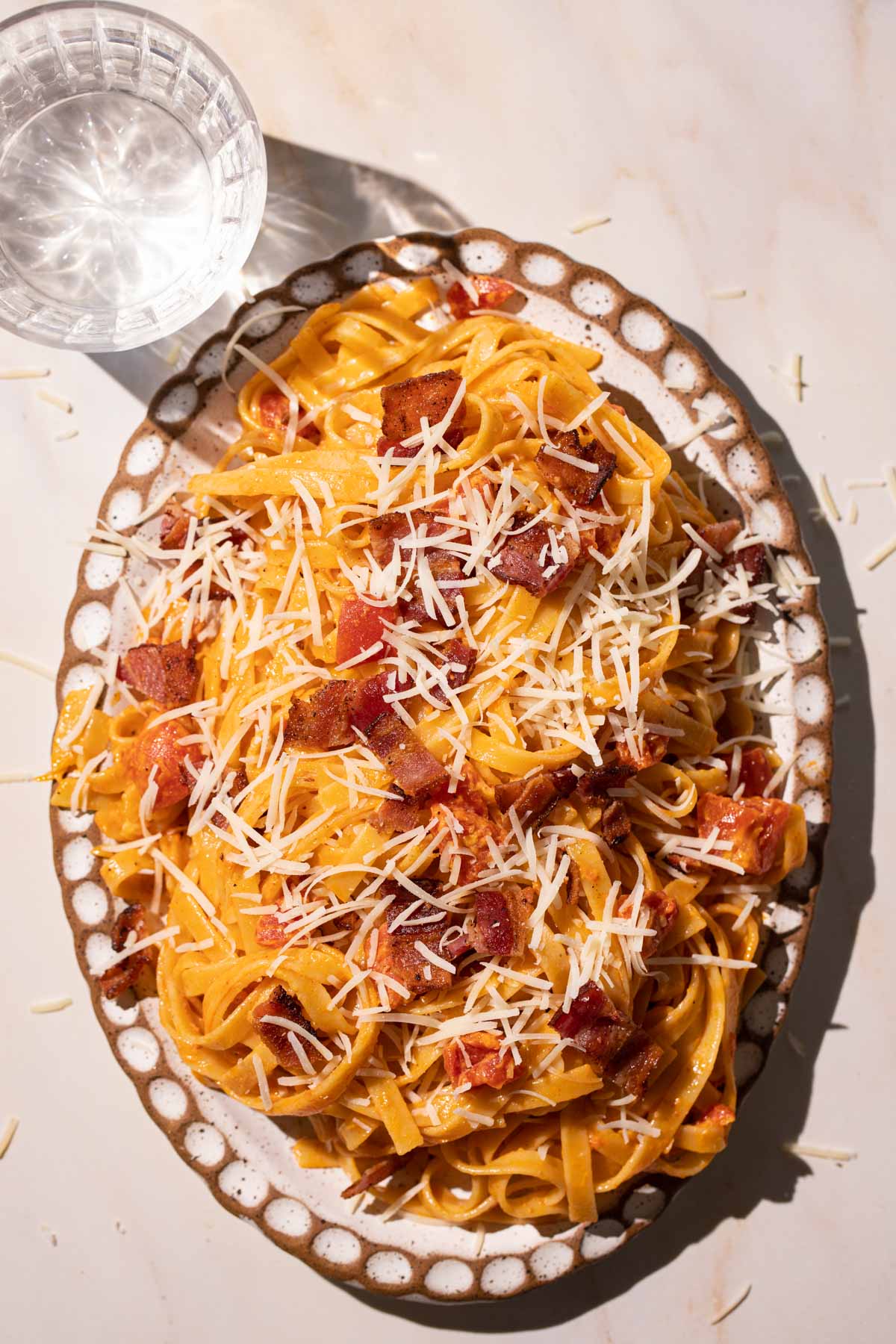 Creamy Tomato Bacon pasta with cheese on a pottery plate