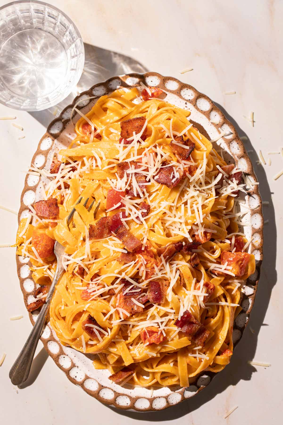 Pasta with bacon and tomatoes on an oval plate