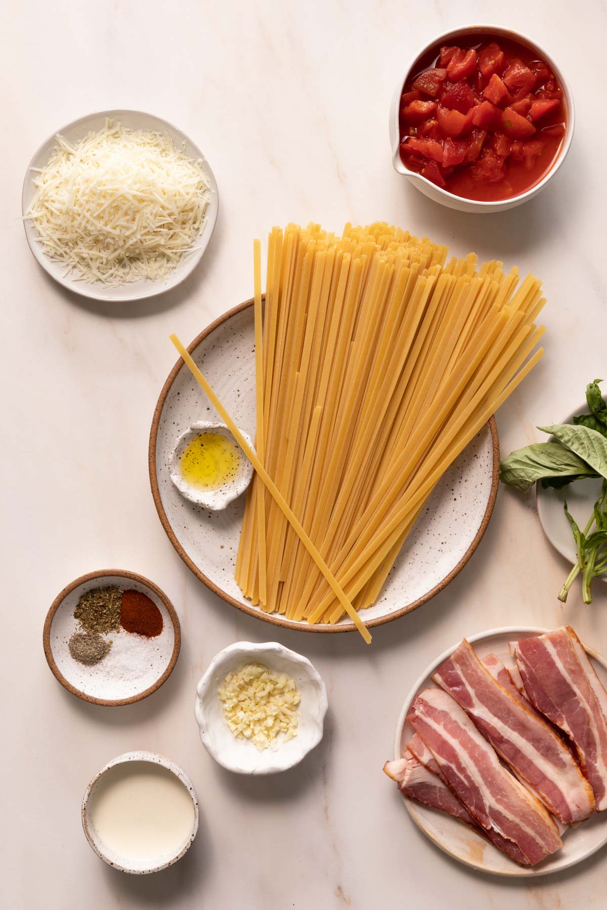 Raw pasta noodles, shredded cheese, canned tomatoes in bowls