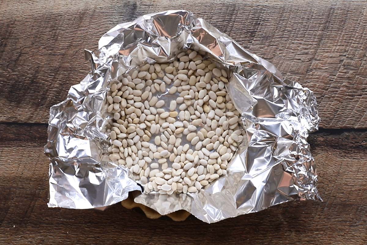 A pie pan with aluminum foil and dried beans for parbaking a pie crust