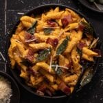 Pumpkin pasta with bacon, sage, and parmesan cheese on a black plate