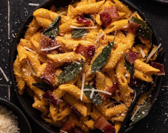 Pumpkin pasta with bacon, sage, and parmesan cheese on a black plate