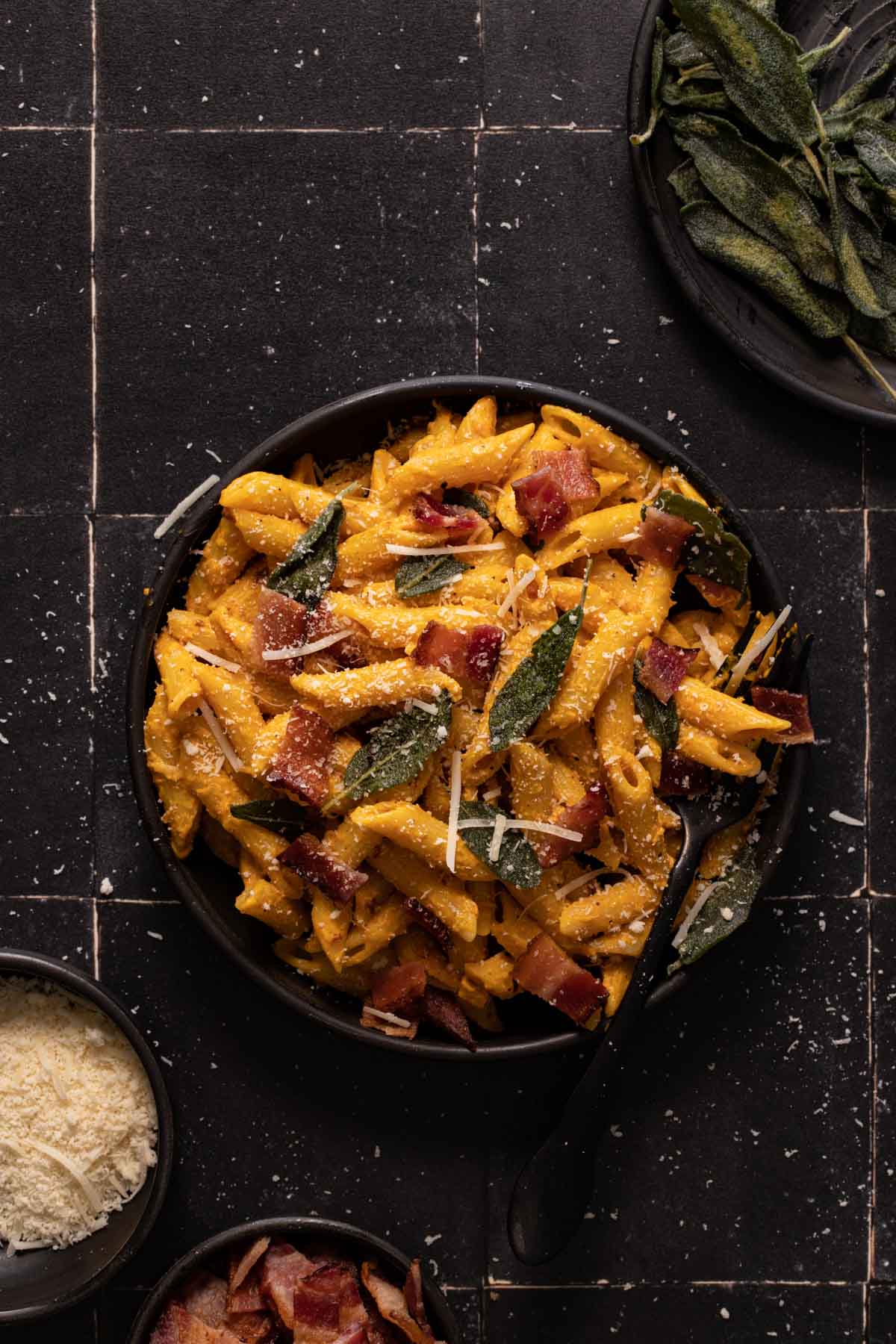 Pumpkin pasta with sage and bacon on a black plate