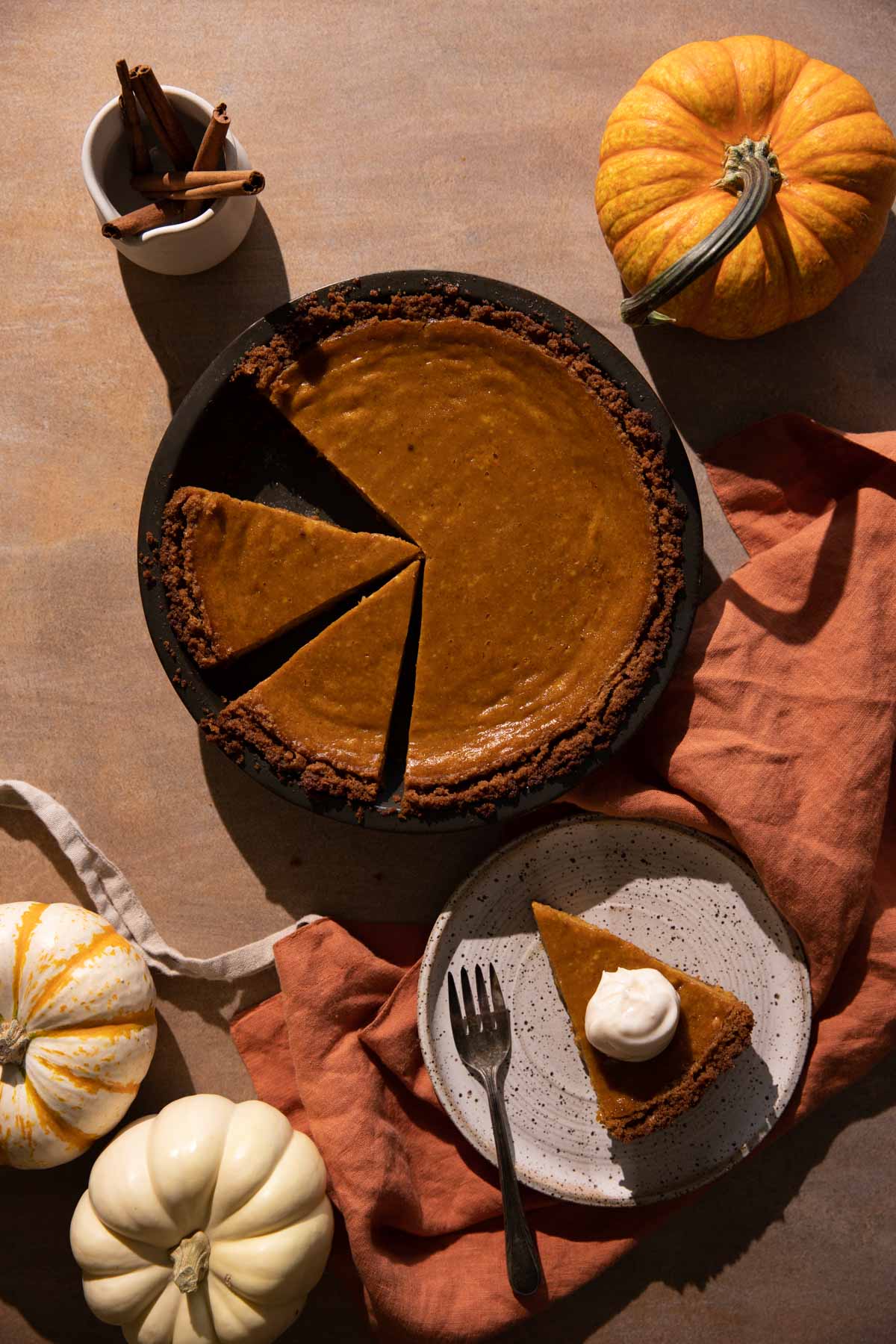 Cream cheese pumpkin pie sliced in a pie pan with pumpkins