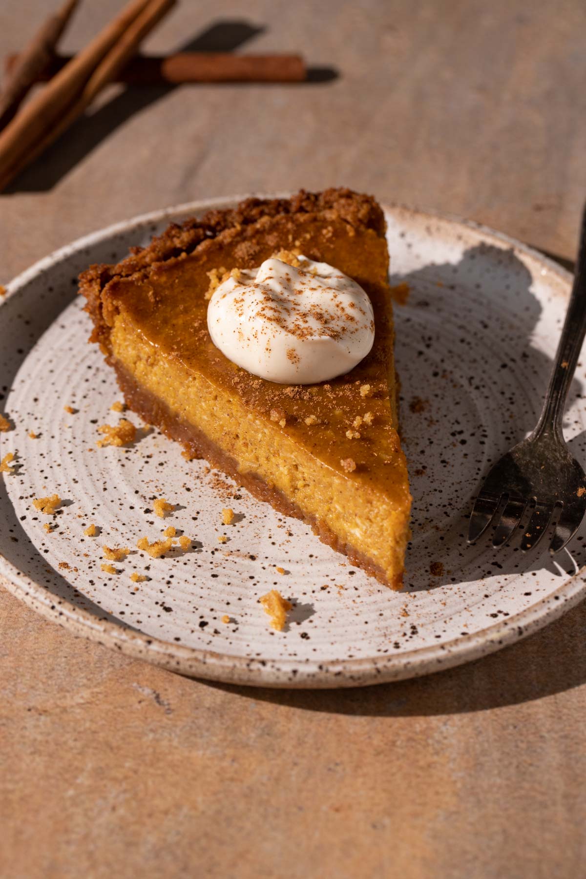 A slice of cream cheese pumpkin pie with whipped cream on a plate