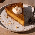 A slice of cream cheese pumpkin pie on a plate with a fork