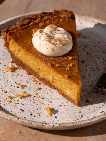 A slice of cream cheese pumpkin pie on a plate with a fork