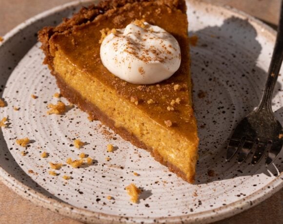 A slice of cream cheese pumpkin pie on a plate with a fork