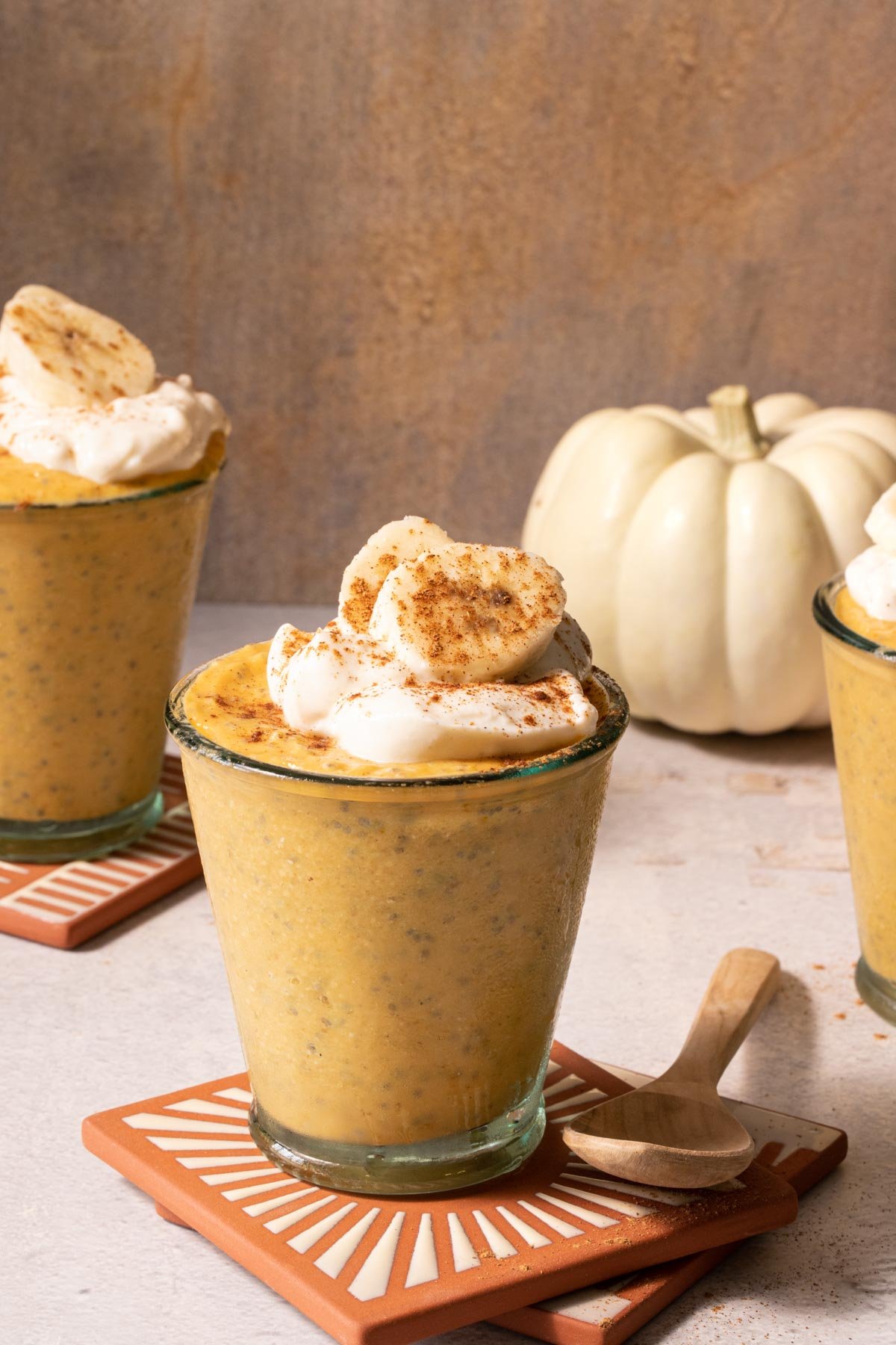 Pumpkin chia pudding in glasses with sliced banana and pumpkins