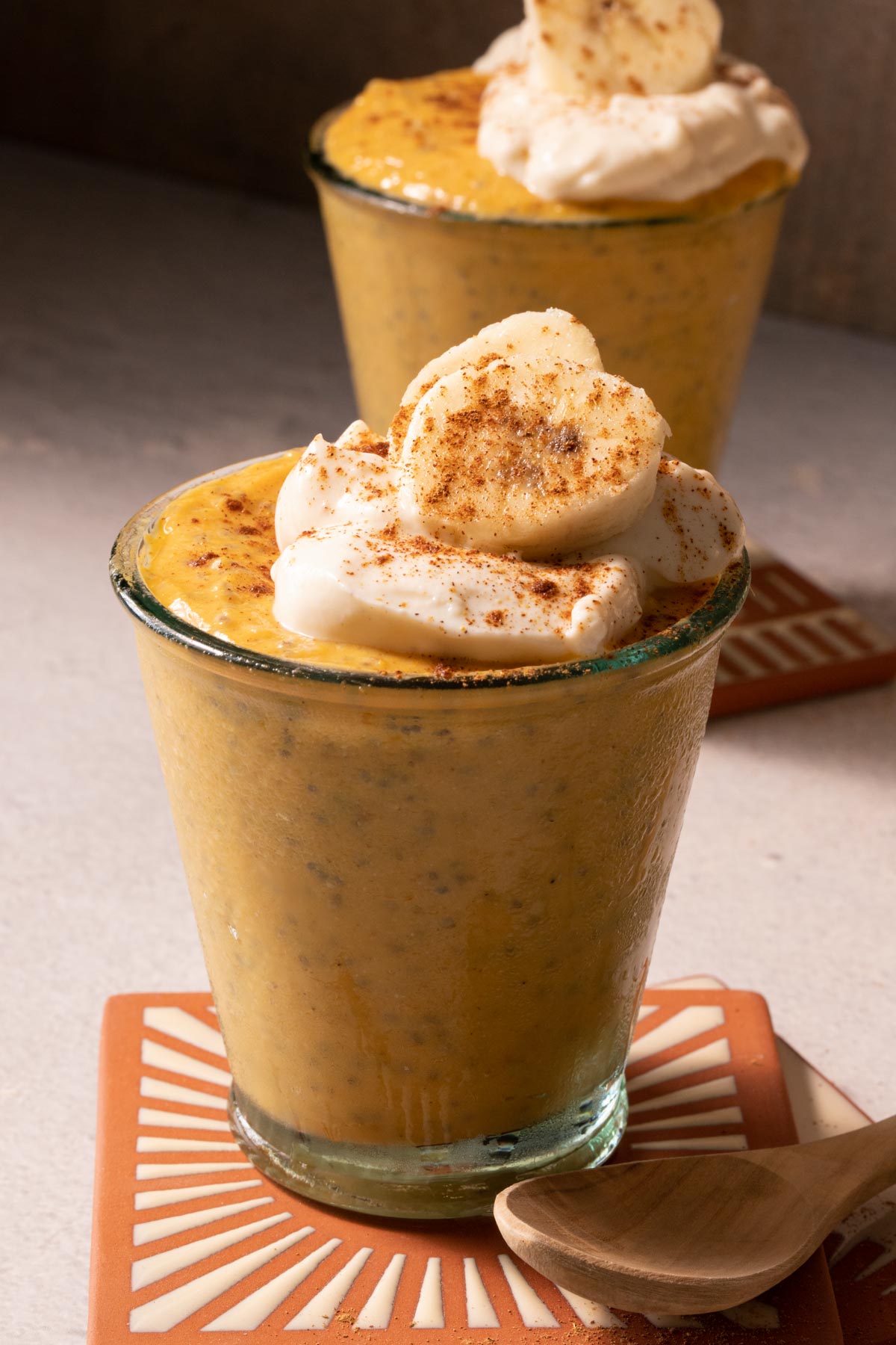 Pumpkin chia pudding in two glasses with bananas and yogurt