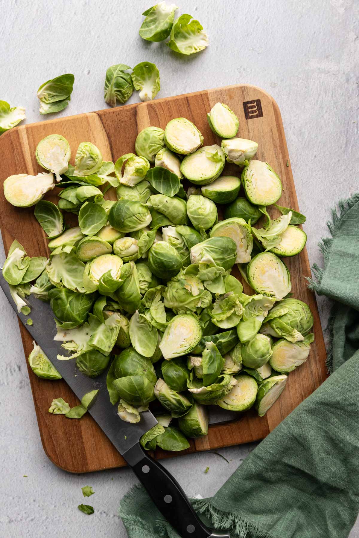 Brussel sprouts sliced on a cutting board with a knife