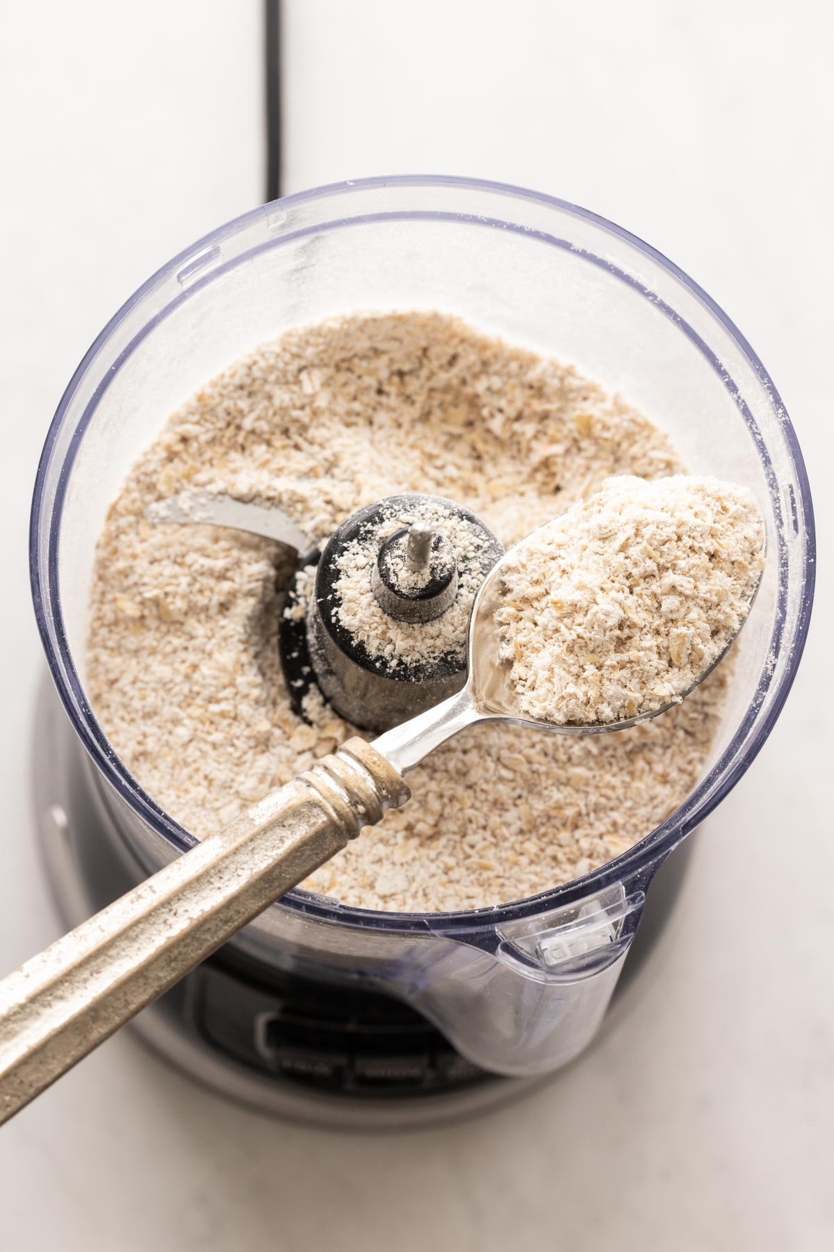 Oats in a mini food processor with a spoon