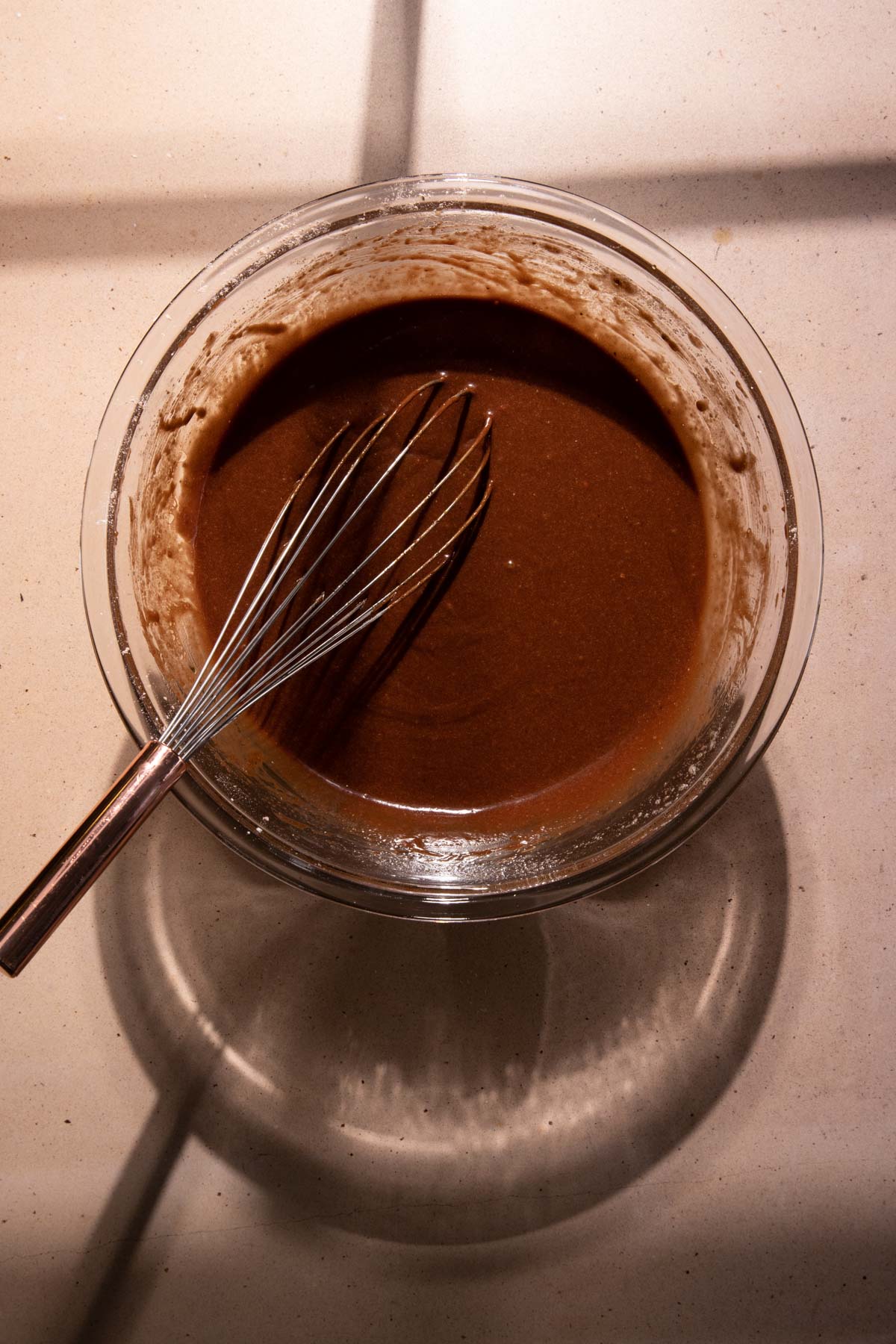 Chocolate financier batter in a bowl with a whisk