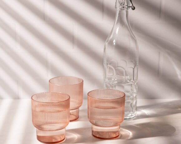 Three pink glasses in light with window blind shadows