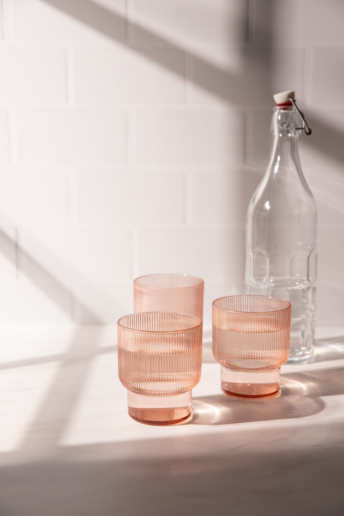 Pink glasses in window light with window shadows