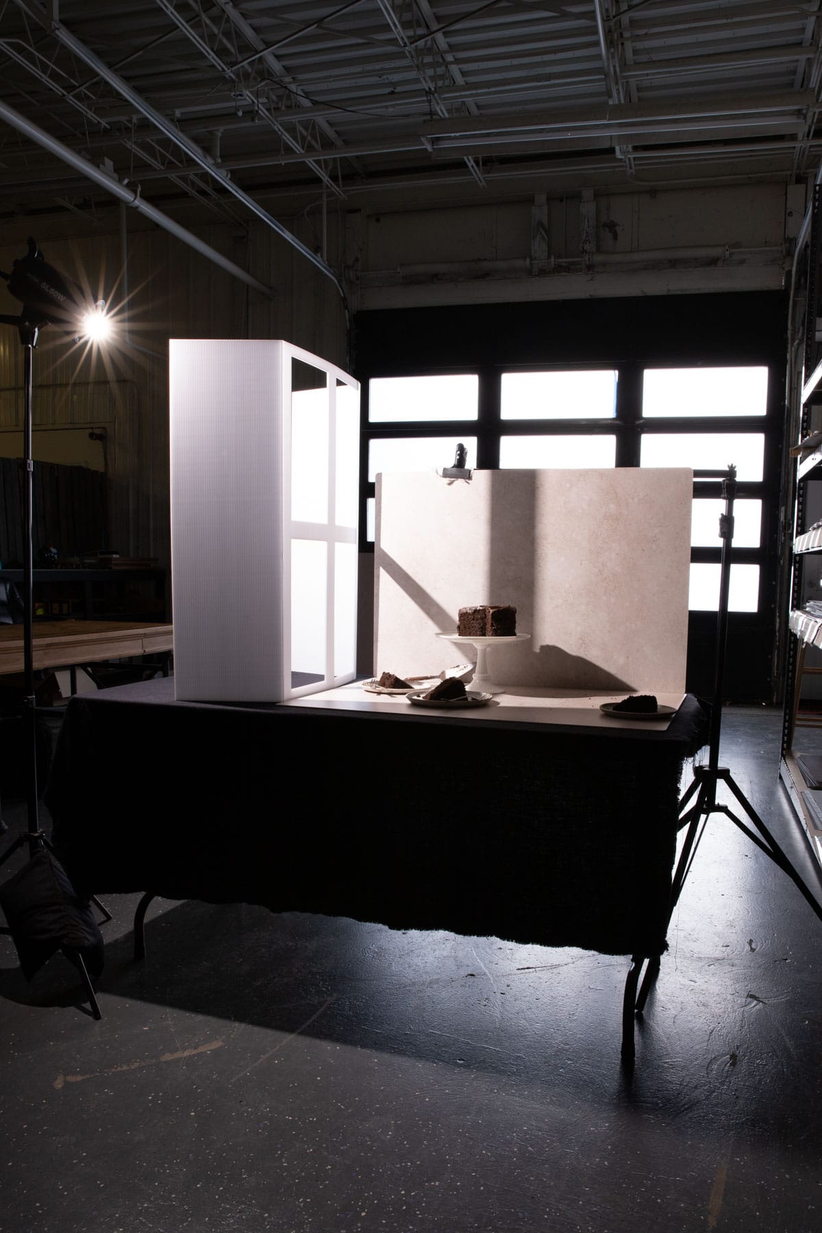 Behind the scenes of a photoshoot of chocolate cake with a fake window and artificial light