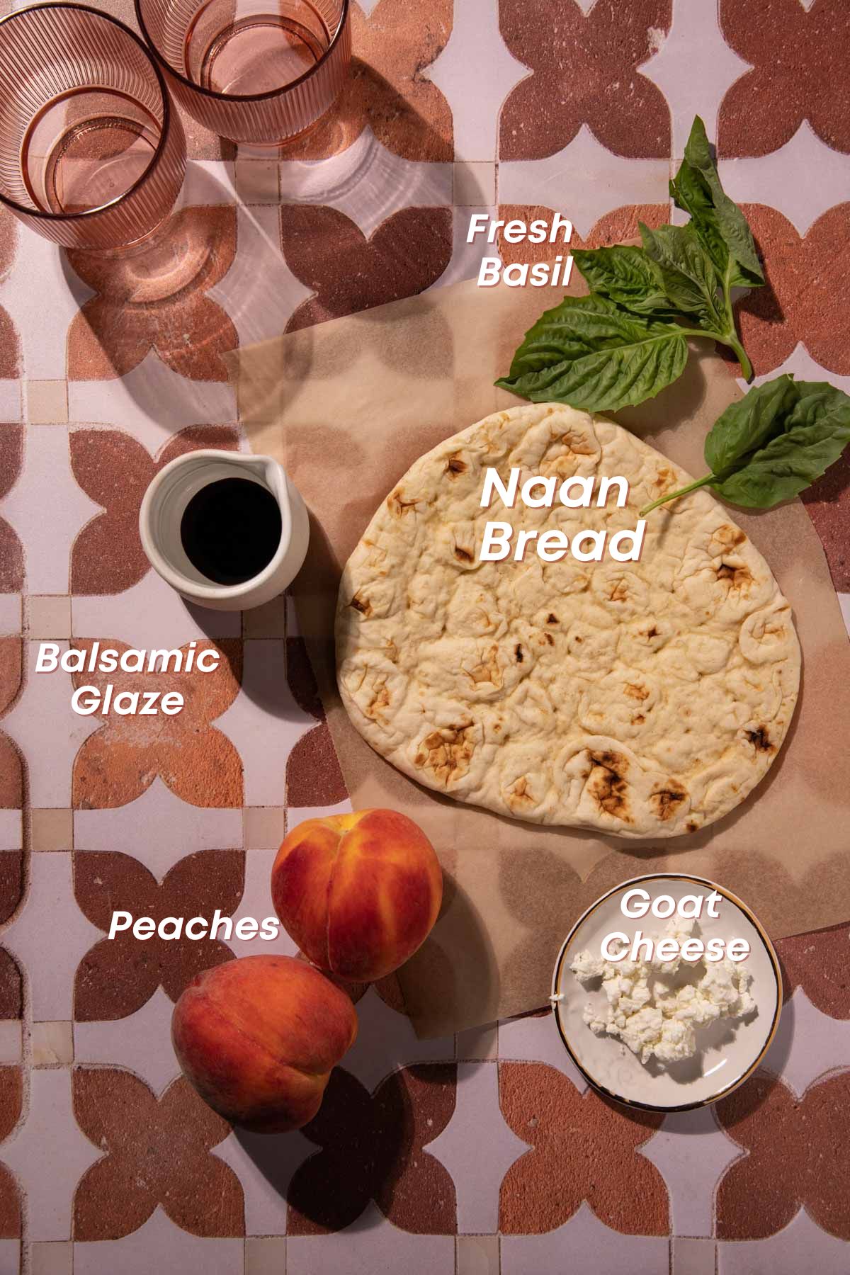 Naan bread, peaches, goat cheese, and basil on pink tile