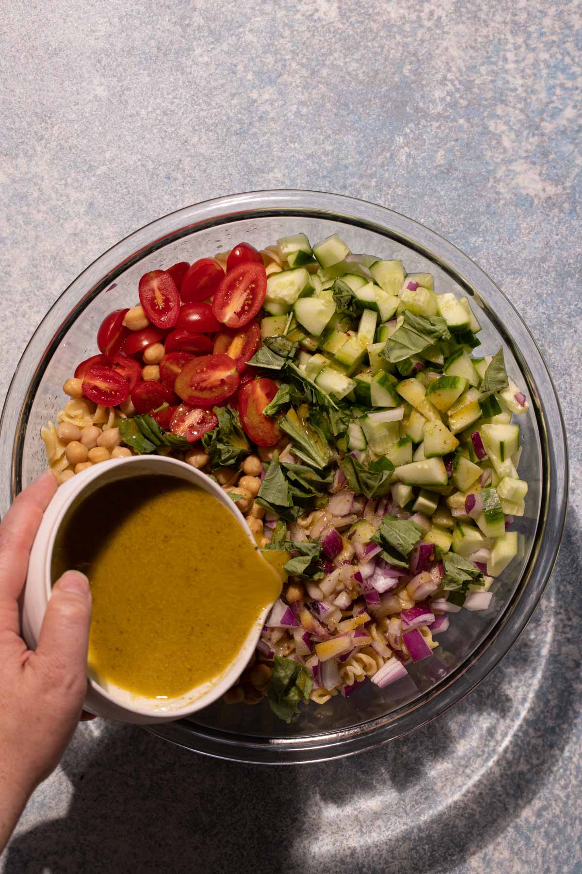 Pouring dressing into the lemon basil chickpea pasta salad