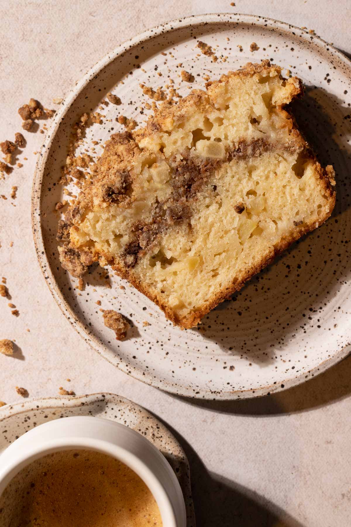 Apple streusel slice on a plate with a cup of coffee