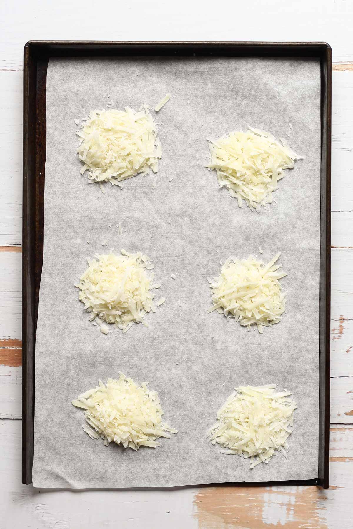 Shredded pecorino Romano cheese crisps on a sheet pan