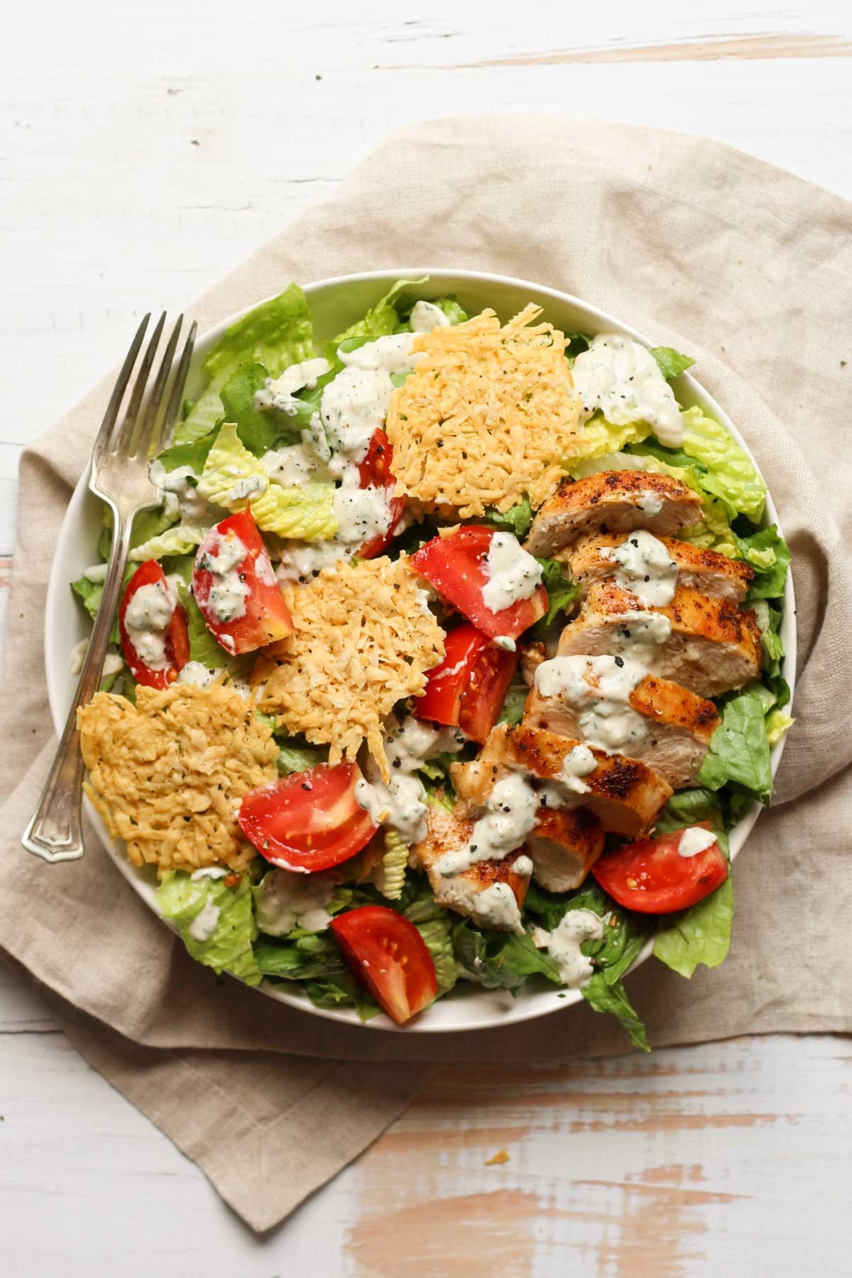 Chicken Caesar salad with tomatoes and cheese crisps in a bowl
