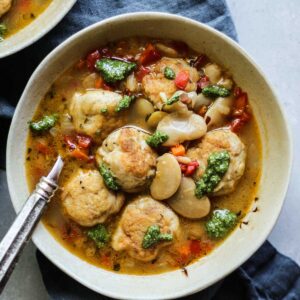 A bowl of chicken meatball soup with pesto
