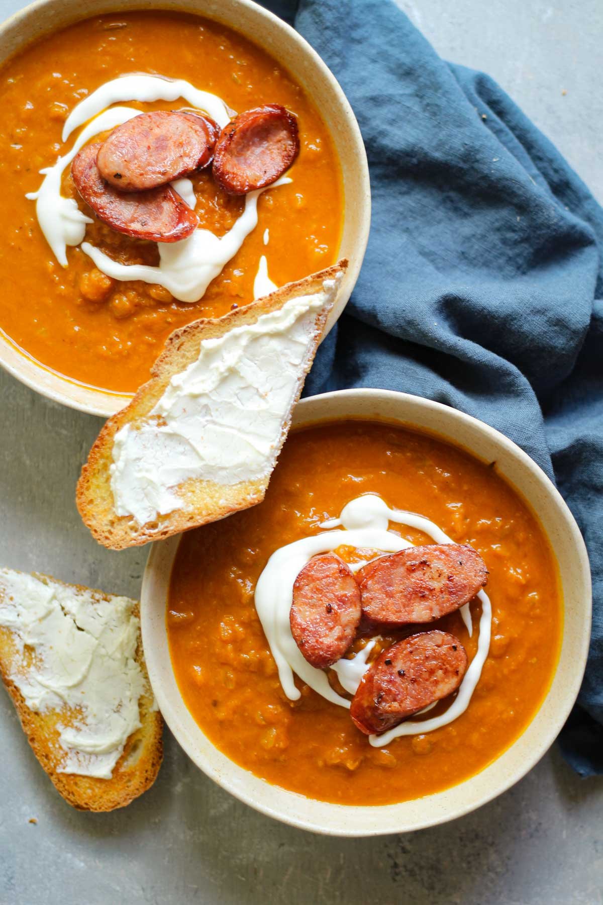 Two bowls of pumpkin butternut squash soup with sausage and goat cheese toast