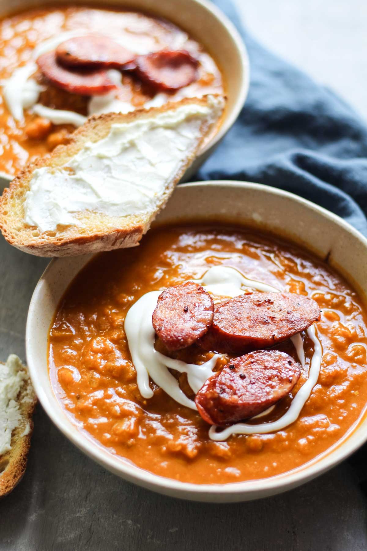 Two bowls of pumpkin butternut soup with cajun sausage 