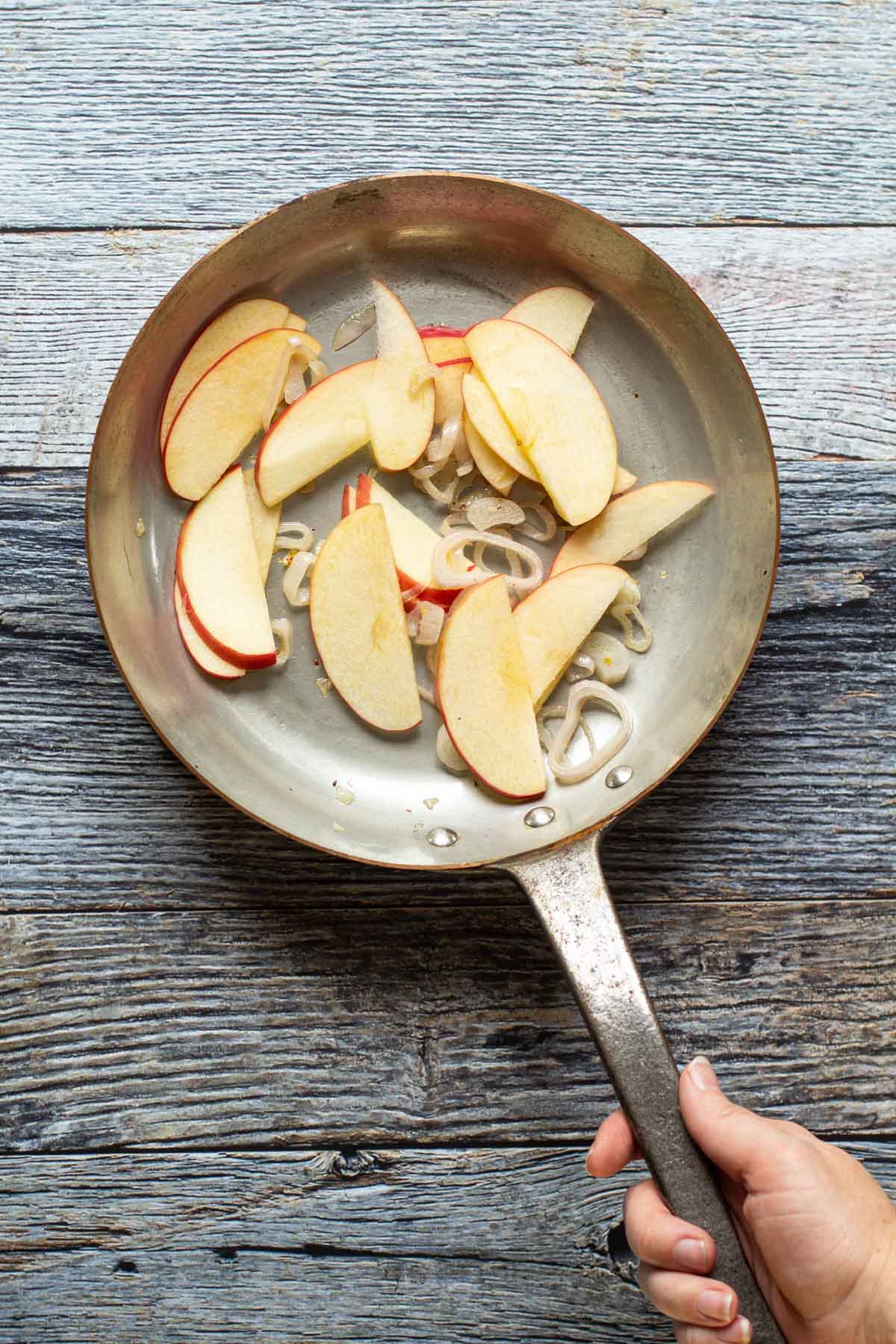 Sliced apples and shallots in a saute pan