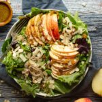 An apple salad with shallots and almonds in a large bowl