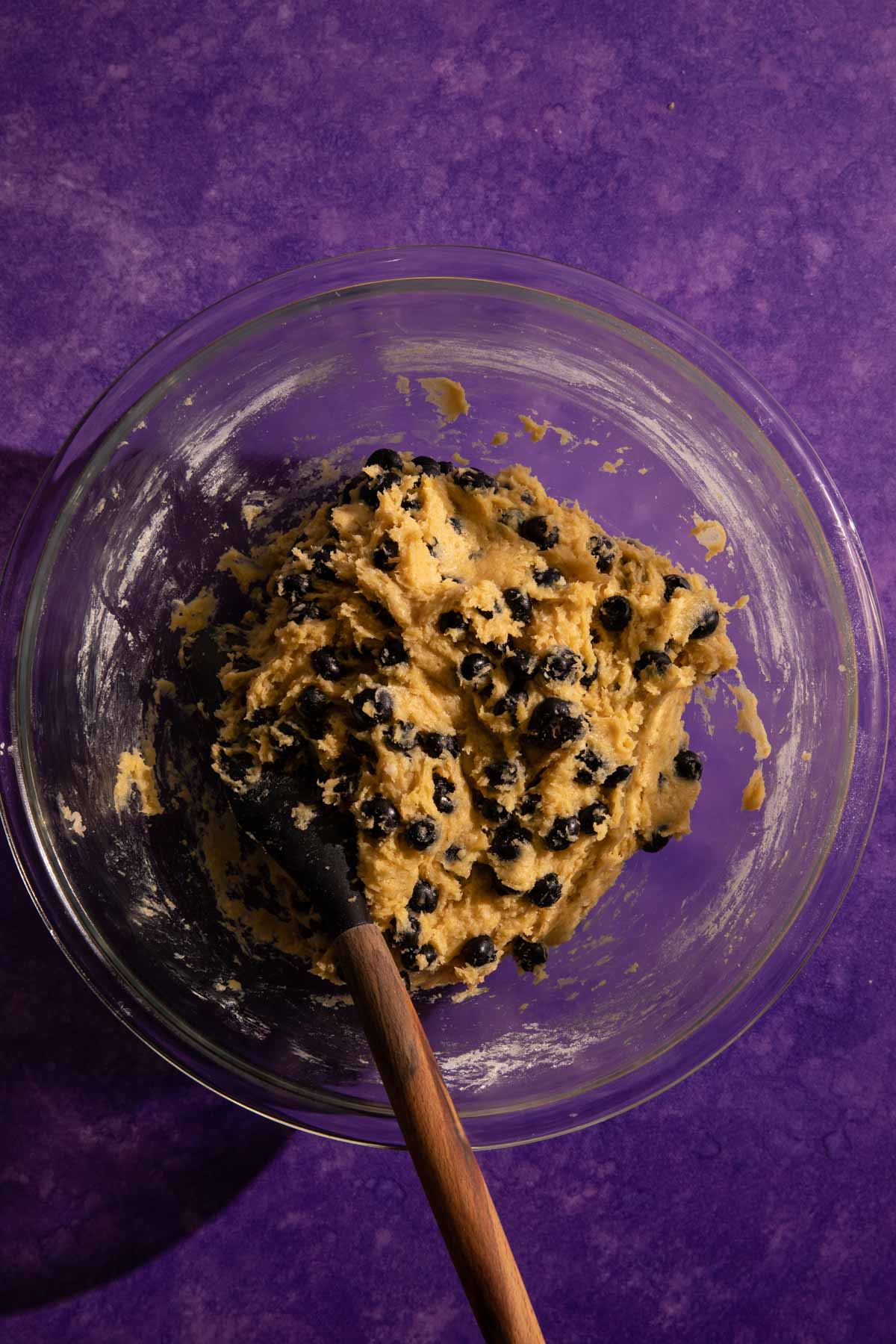 Blueberry muffin batter in a glass bowl with a spatula