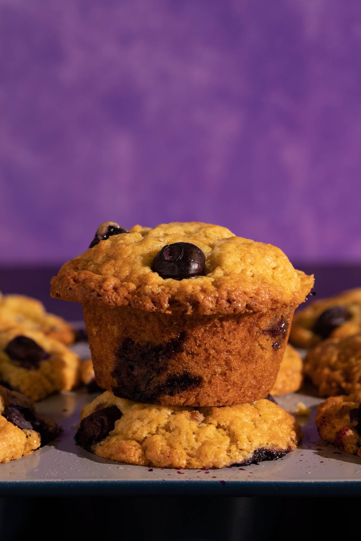 A blueberry muffin on top of a muffin tin