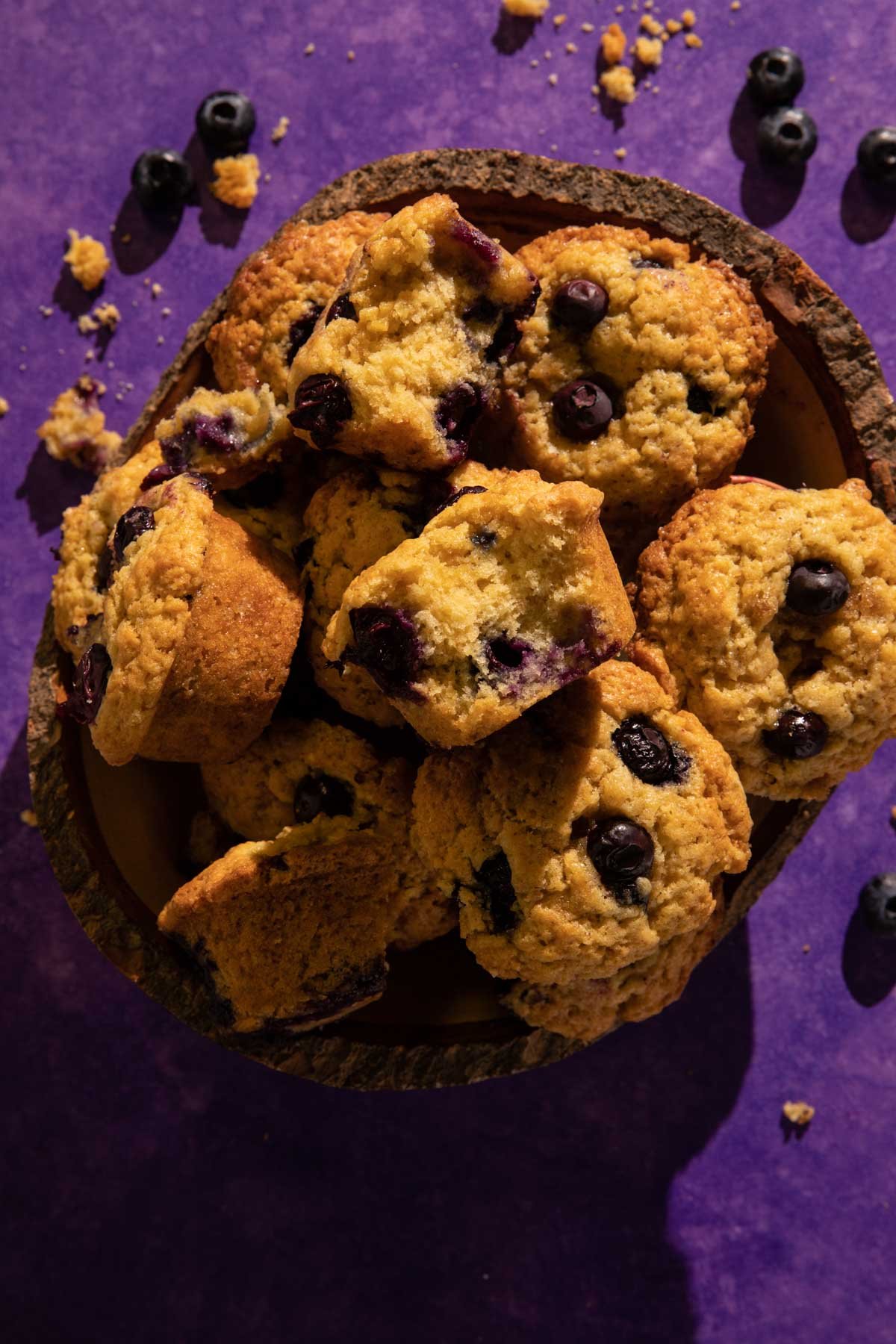 A pile of blueberry muffins in a wooden bowl