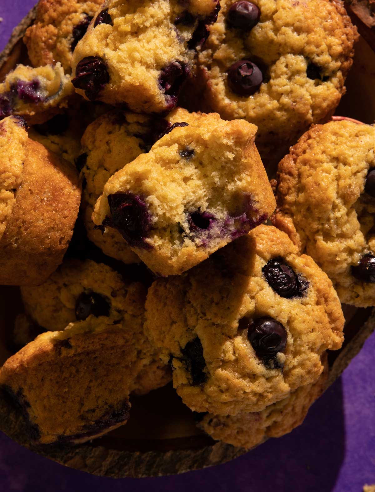 Blueberry muffins in a pile with a bite taken out of one.