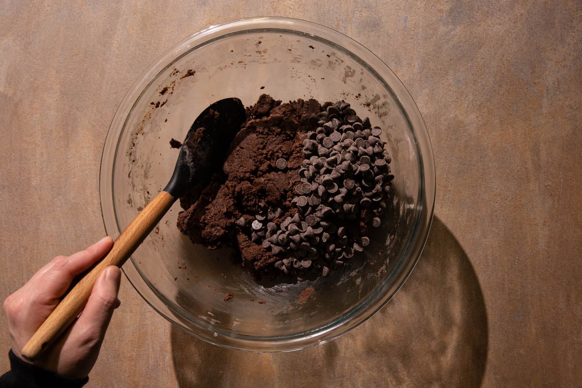 Double chocolate skillet dough and chocolate chips in a bowl being stirred