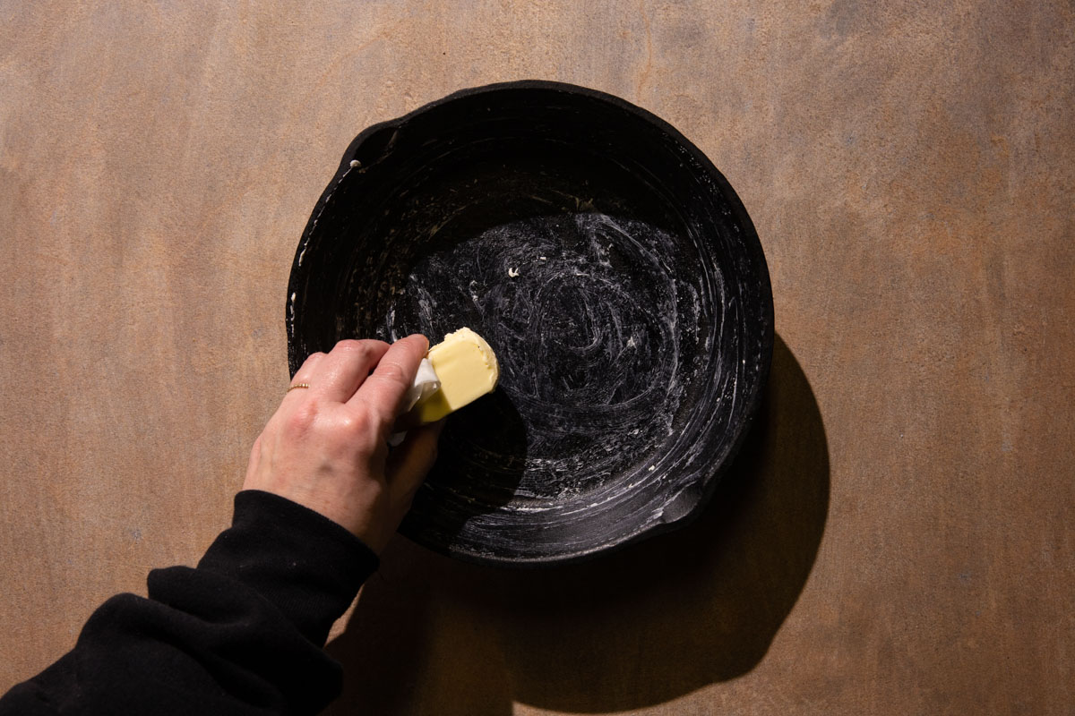 Butter being smeared into a cast iron skillet