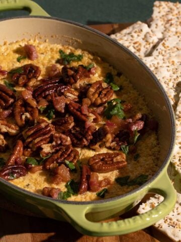 An oven dish with baked goat cheese dip, garnished with toasted pecans.